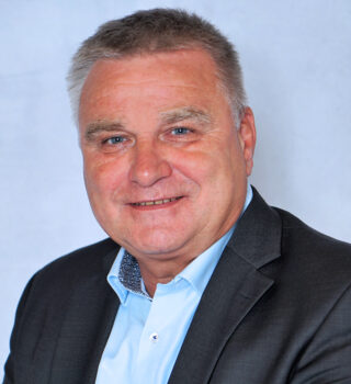 Detlef Opitz. Ein Mann mit kurzen grauen Haaren. Er trägt ein Jackett und ein blaues Hemd