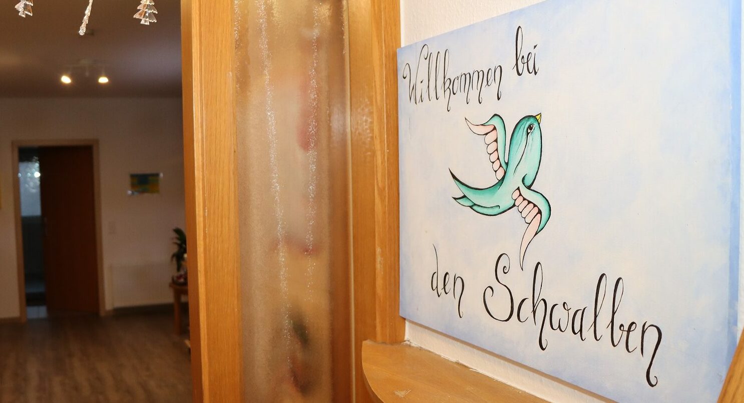 Man sieht den Flur mit dem Willkommensschild der Wohngruppe