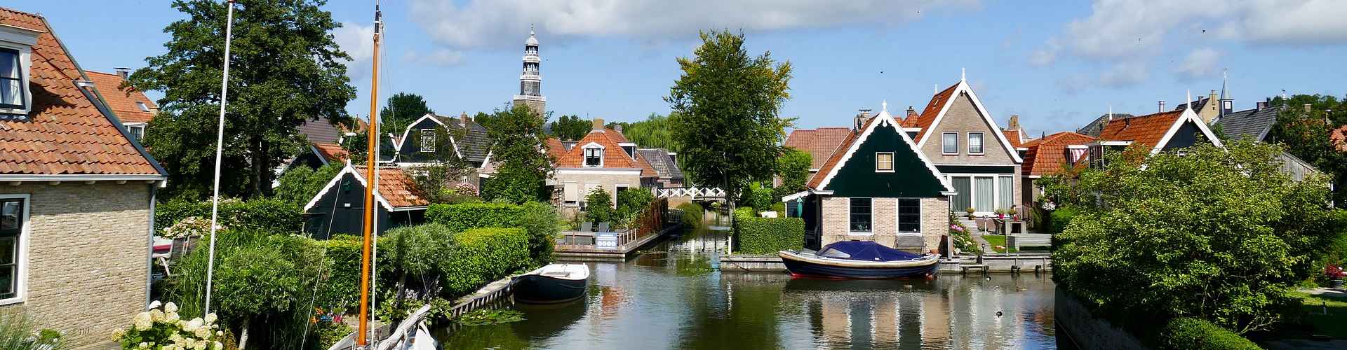 Eine Ortslandschaft mit Häusern. Ein Kanal mit Boote