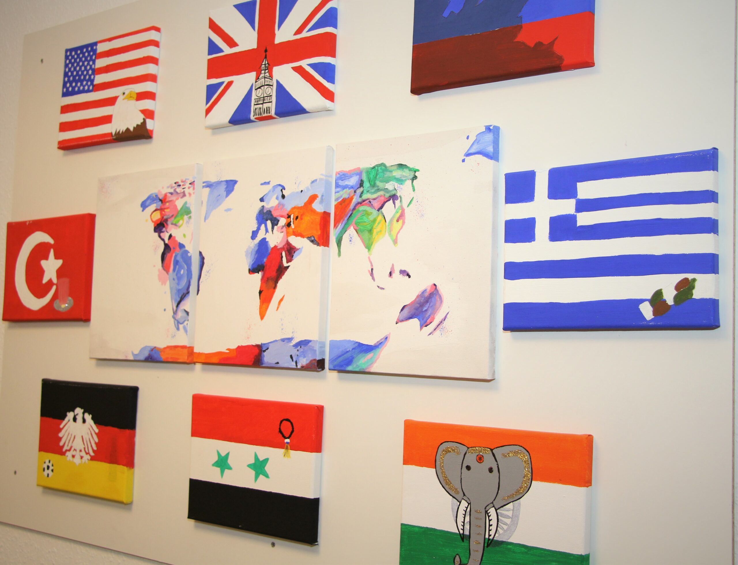 Man sieht gemalte Plakate mit verschiedenen Länderflaggen und eine gemalte Weltkarte