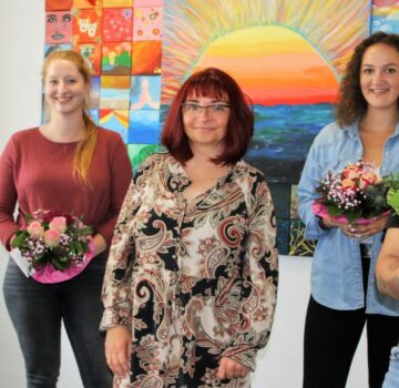 Man sieht jungen Frauen mit Blumensträuße und eine GPS Mitarbeiterinnen in der Mitte