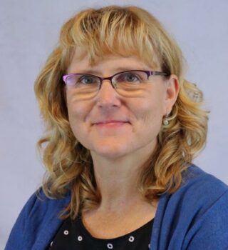 Christina Laufer-Dada. Eine lächelnde Frau mit einer Brille und mit mittellangen blonden Haaren