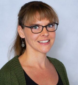 Mareike Dilger. Eine lächelnde Frau mit mittelblonden langen Haaren. Sie hat eine Brille und trägt Ohrringe