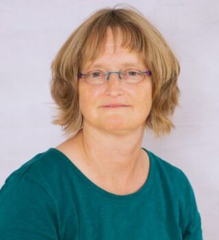Anja Gellert. Eine Frau mit einer Brille und schulterlangen blonden Haaren