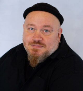 Jörg Lammers. Ein Mann mit Mütze und Bart. Er hat ein Piercing und ein Ohrring