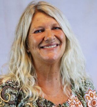 Sylke Petri. Eine lächelnde Frau mit grauen langen Haaren