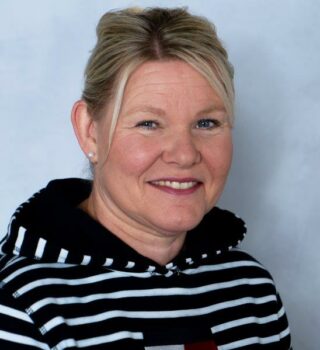 Kerstin Tammen. Eine lächelnde Frau mit blonden Haaren. Sie trägt Ohrringe