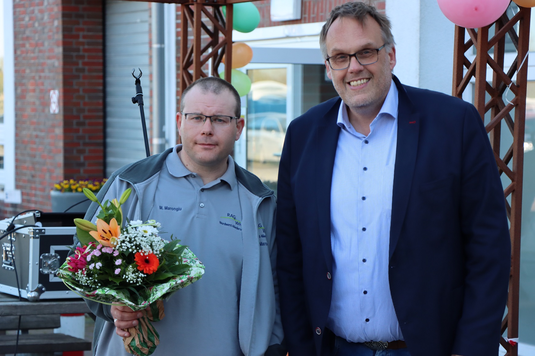 Geschäftsführer Klaus Puschmann und ein Beschäftigter von der GPS. Der Beschäftigte hält einen Blumenstrauß in der Hand